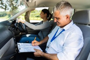 A driving examiner with a student in a car